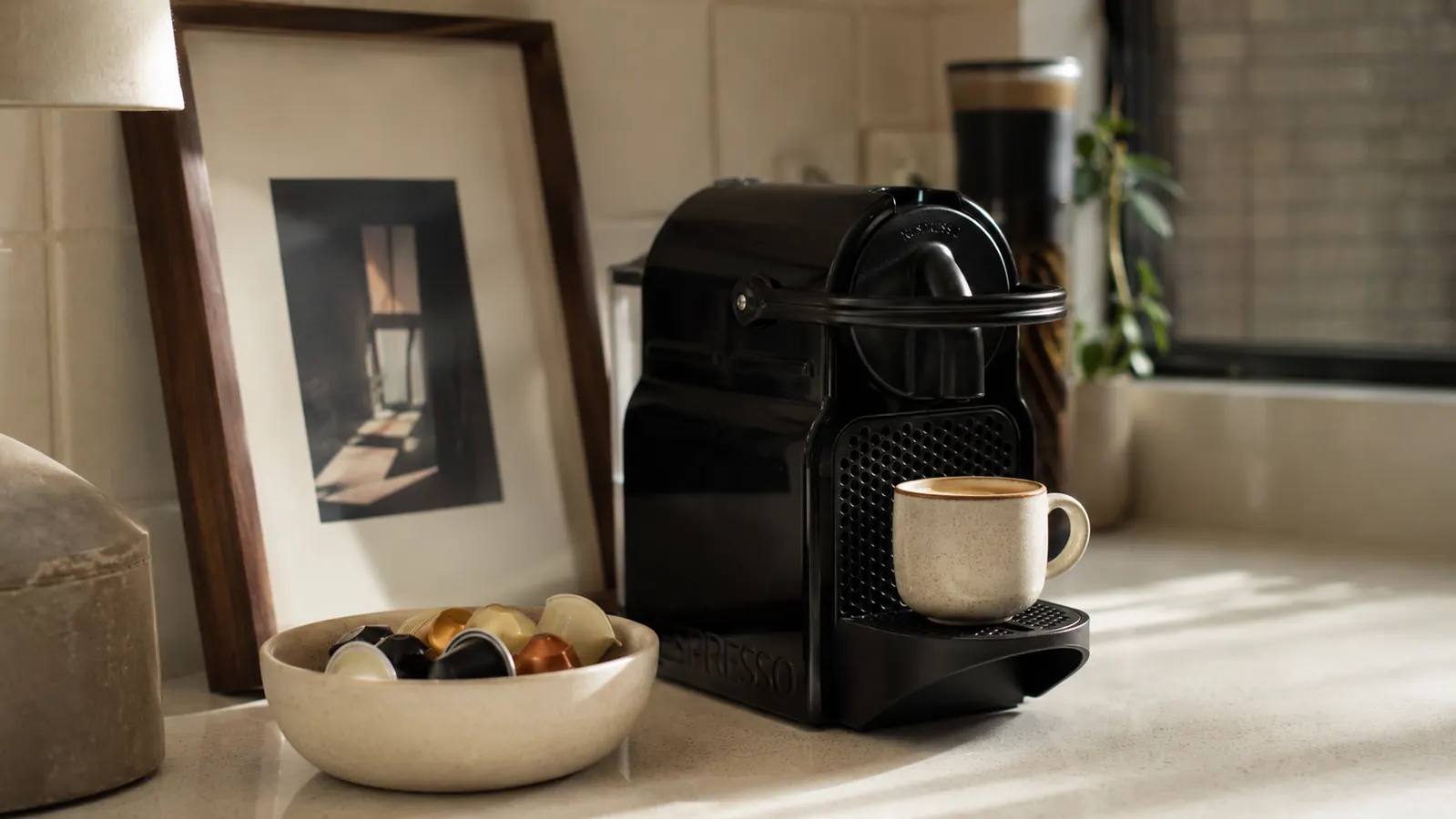 Nespresso Inissia espresso machine on a small apartment kitchen counter with morning light coming through a window